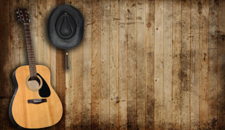 cowboy-hat-and-guitar-against-an-old-barn