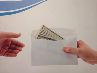 Envelope of 100 dollar bills being handed from one person to another. Envelope of 100 dollar bills being handed from one person to another.