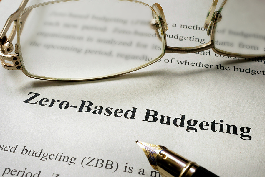 Shows a person's glasses and pen with the words zero based budgeting on the paper underneath Shows a person's glasses and pen with the words zero based budgeting on the paper underneath