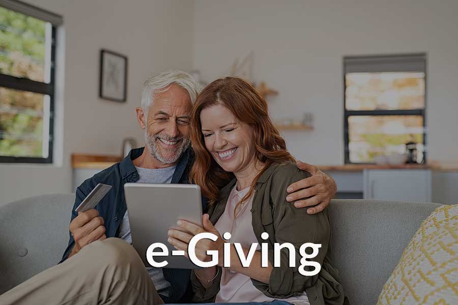 A couple giving to their church through a mobile device and the church's e-Giving platform. A couple giving to their church through a mobile device and the church's e-Giving platform.